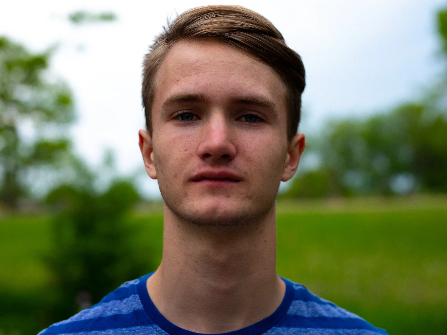 Portrait of a young man in a blue shirt outdoors