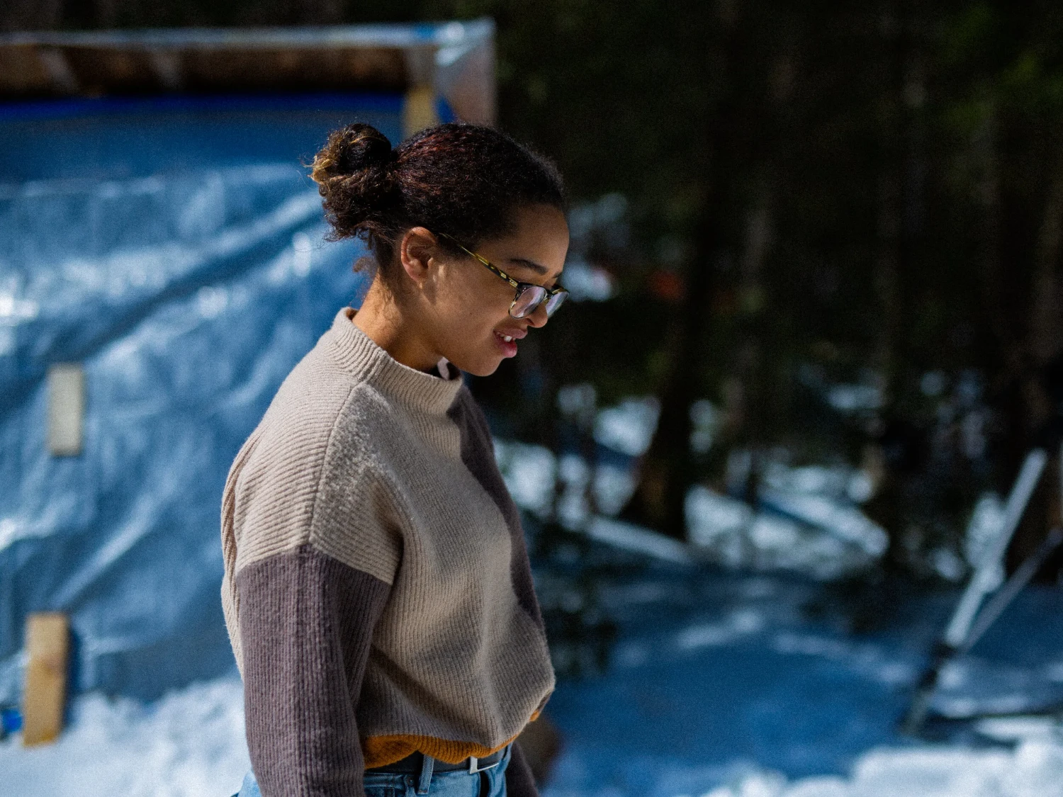 A woman with glasses standing outside beside a snowy deck