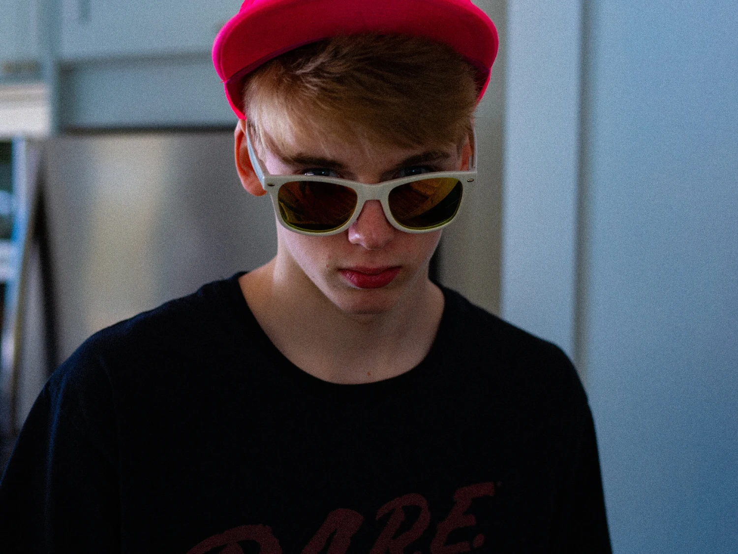 A young man wearing a red cap and white sunglasses