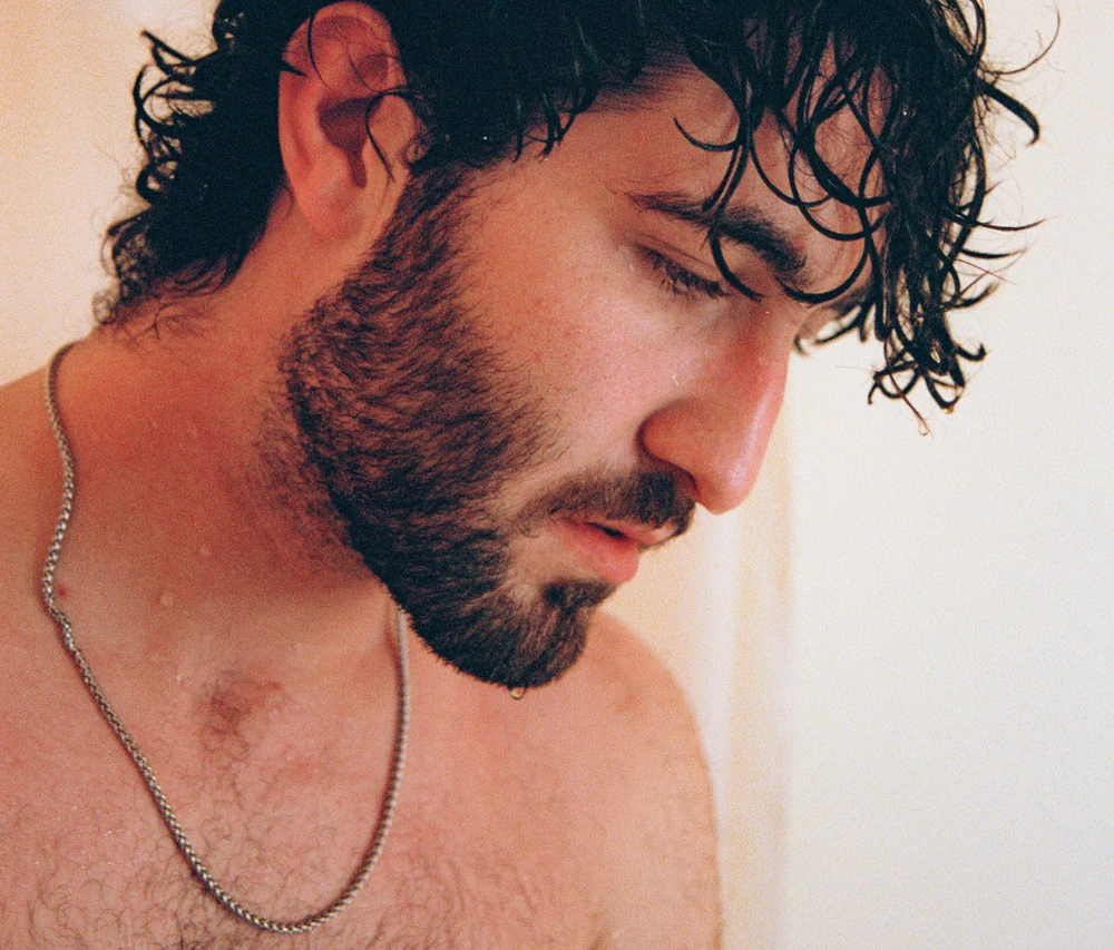 Close-up of a man looking down, wearing a silver chain