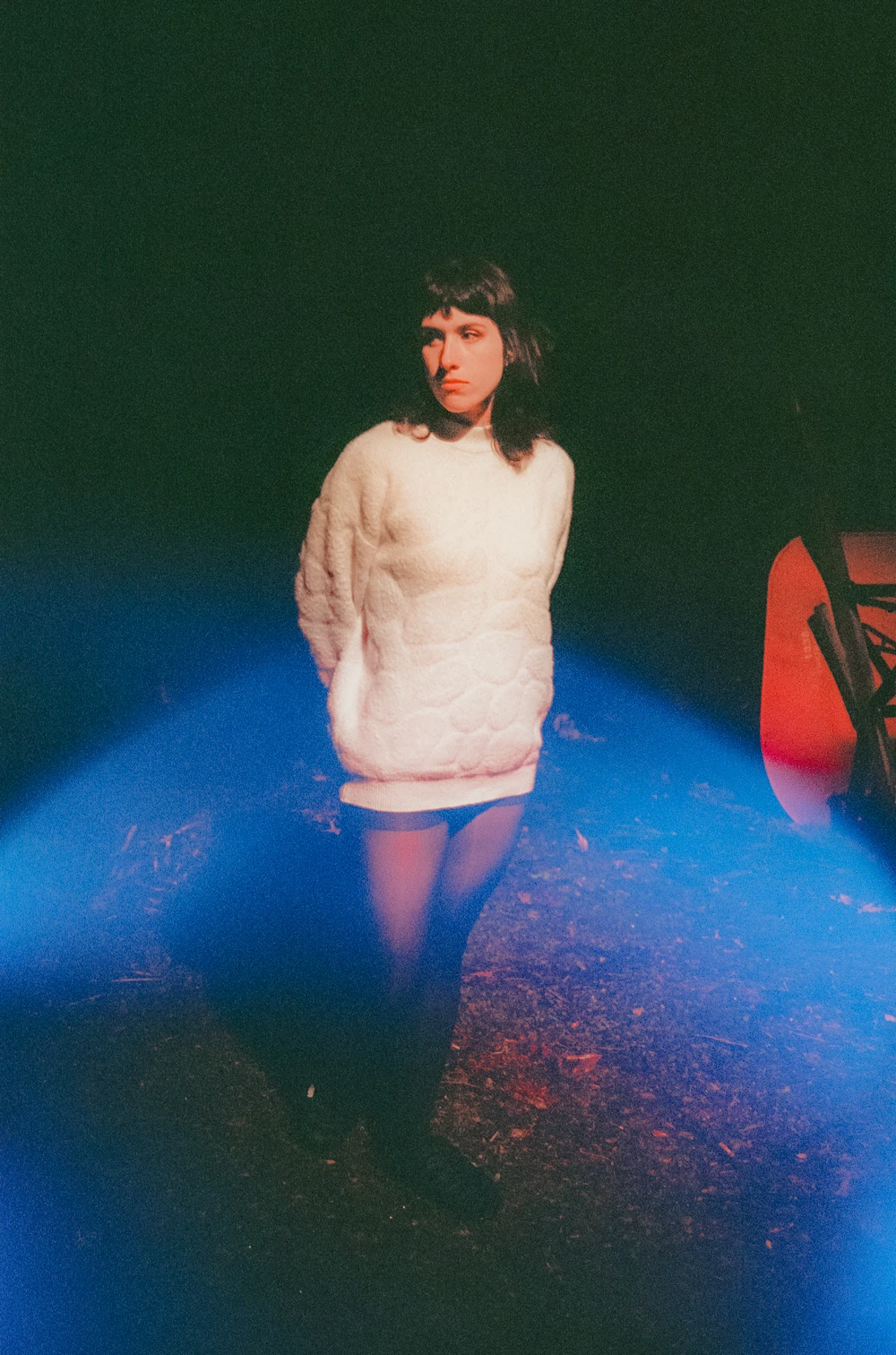 A woman in a light sweater illuminated by blue light at night